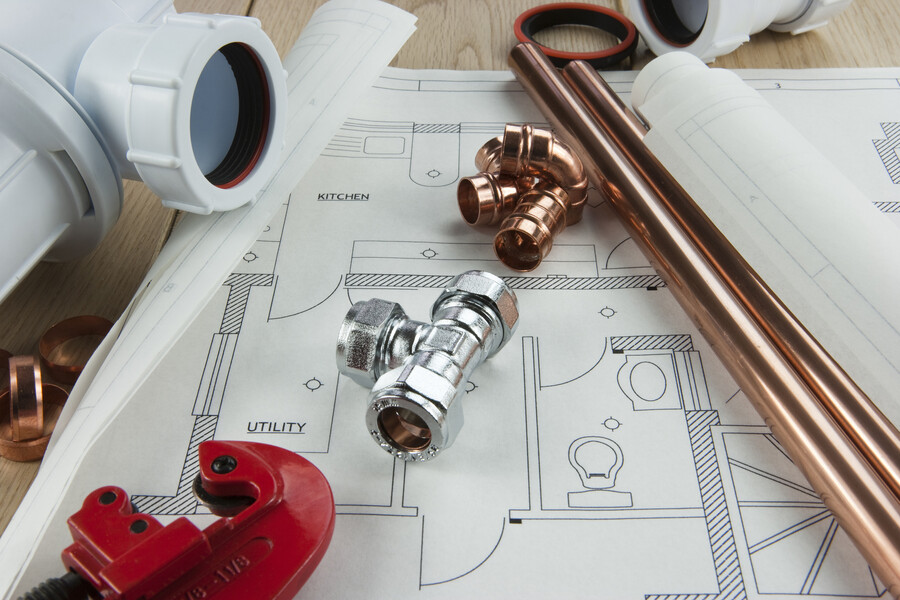 Plumbing pipes, fittings and tools laid out on a house plumbing blueprint পরিকল্পনা
